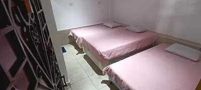 two beds in a small room with pink sheets at Hostal Santa Marta in La Unión