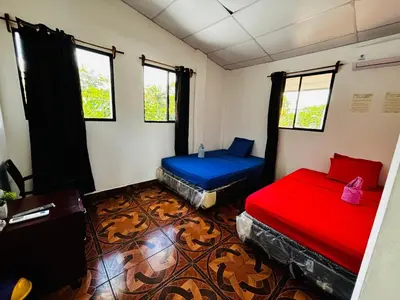 a room with two beds and two windows at LA CASONA SV Hostal in La Libertad