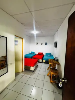 a room with three beds in a room with a door at LA CASONA SV Hostal in La Libertad