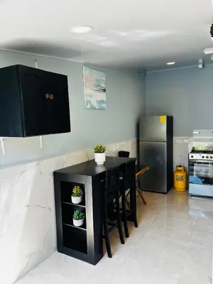 a kitchen with a black table and a refrigerator at Hostal Camila’s in Tamanique