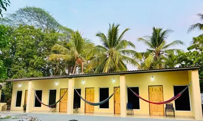 a yellow building with hammocks in front of it at Hostal Camila’s in Tamanique