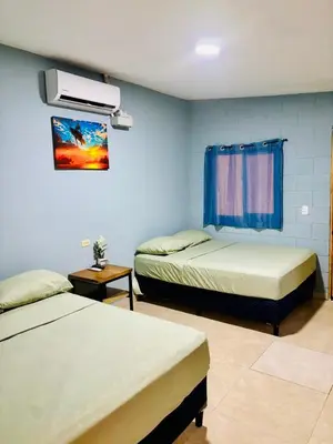 a room with two beds and a tv on the wall at Hostal Camila’s in Tamanique