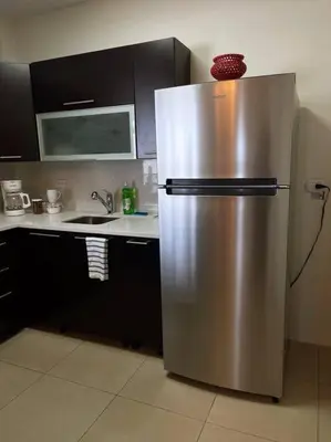 a stainless steel refrigerator in a kitchen with black cabinets at Encanto Urbano in San Salvador