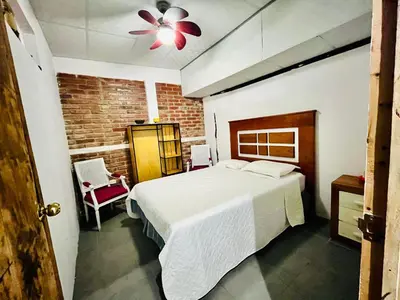 a bedroom with a white bed and a brick wall at Entre tejas in Concepción de Ataco