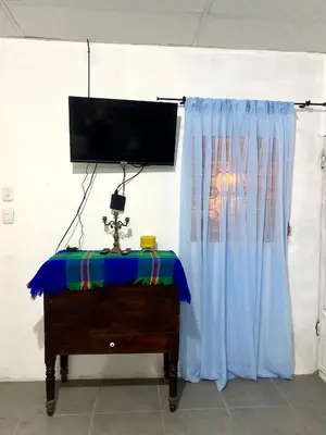 a room with a tv and a dresser with a blue curtain at Entre tejas in Concepción de Ataco