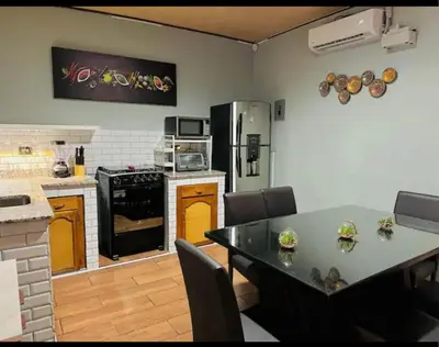 a kitchen with a table and a refrigerator at Enjoy Your Vacation at Tone'y House in Chalchuapa