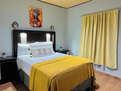 a bedroom with a large bed with a yellow blanket at Enjoy Your Vacation at Tone'y House in Chalchuapa