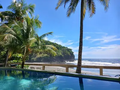 a swimming pool with palm trees and the beach at El Patio de Don Moncho - Shalpa in Jicalapa