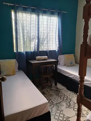 a room with two beds and a table and a window at El Patio de Don Moncho - Shalpa in Jicalapa