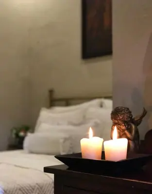 two candles on a table in front of a bed at Casa Degraciela - Hotel Boutique in Concepción de Ataco