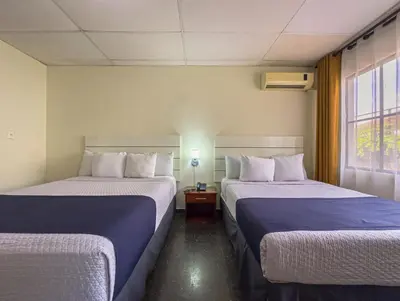 a hotel room with two beds and a window at Cardedeu Suites in San Salvador
