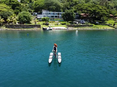 a woman standing on a paddle board in the water at Cardedeu Hotel Lago de Coatepeque in El Congo