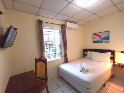 a bedroom with a bed with two white shoes on it at Hotel Armonía Hostal in San Salvador