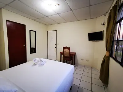 a bedroom with a white bed and a chair at Hotel Armonía Hostal in San Salvador