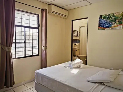 a bedroom with a bed and a large window at Hotel Armonía Hostal in San Salvador