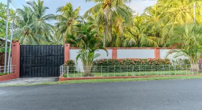 a fence in front of a house with palm trees at San Diego Beach House, near La Lib and Surf City in La Libertad