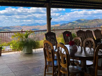 a table and chairs on a balcony with a view of mountains at Hotel y Restaurante La Perla, Cacaopera, Morazan, El Salvador in Cacaopera