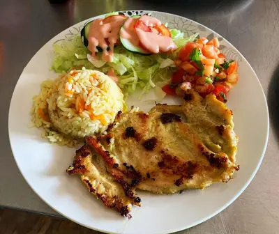 a plate of food with chicken and rice and vegetables at Hotel y Restaurante La Perla, Cacaopera, Morazan, El Salvador in Cacaopera