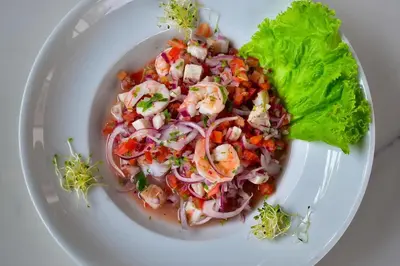 a white plate with a salad with shrimp and lettuce at The Views Resort in El Zonte