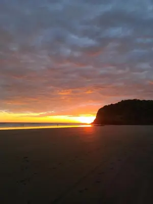 a sunset on a beach with footprints in the sand at Bella Vista Hotel Boutique in San Miguel