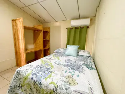 a small room with a bed and a green curtain at Casa De Playa El Encanto in El Porvenir