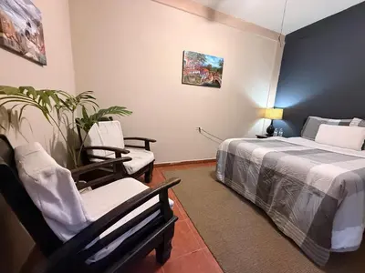 a bedroom with a bed and a chair and a plant at Los Portones de Ataco in Concepción de Ataco