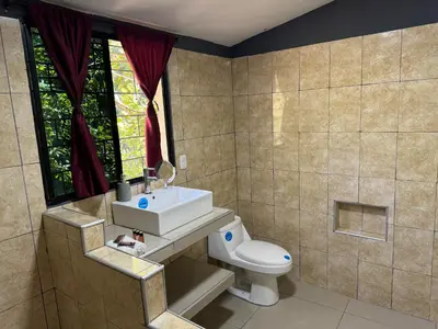a bathroom with a toilet and a sink and a window at El mangal B&B in Suchitoto