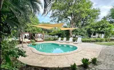 a swimming pool with chairs and a large umbrella at Hotel Zelen in Tamanique
