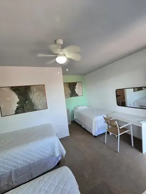 a hotel room with two beds and a desk at Hotel Zelen in Tamanique