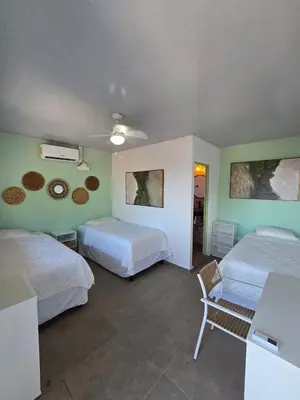 a hotel room with two beds and a chair at Hotel Zelen in Tamanique