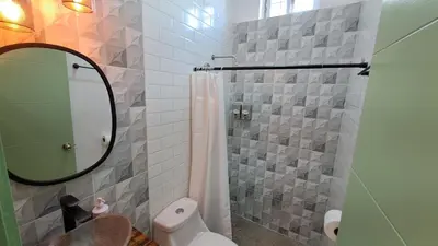 a bathroom with a shower and a toilet and a mirror at Hotel Zelen in Tamanique