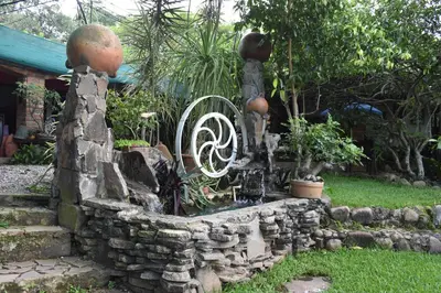 a fountain in a garden with a stone wall at The Mayan Grouper in Suchitoto