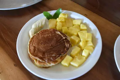 a white plate with a pancakes and fruit on a table at The Mayan Grouper in Suchitoto