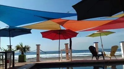 a group of umbrellas and chairs next to a pool at MARDEORO BEACH HOUSE in Barra de Santiago