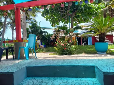 a patio with two blue chairs and a table at MARDEORO BEACH HOUSE in Barra de Santiago