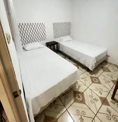 two beds in a room with a tiled floor at Hostal Villa Marta in Santa Ana