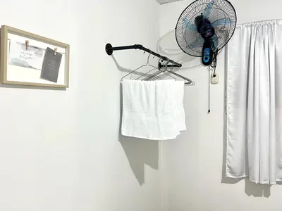 a white bathroom with a fan and a towel at Hostal Villa Marta in Santa Ana
