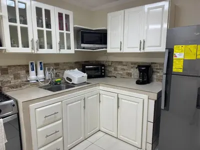 a kitchen with white cabinets and a sink and a refrigerator at Merliot, Sta Tecla Frente Cto Comer La Plaza Merliot in Nueva San Salvador