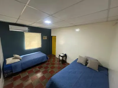 two beds in a room with blue walls at Surf City Town House in La Libertad