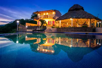 a villa with a swimming pool at night at Hotel Los Mangos El Salvador in El Cuco