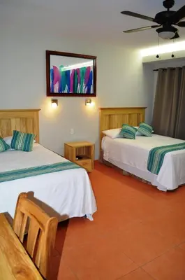 two beds in a room with a tv on the wall at Hotel Los Mangos El Salvador in El Cuco