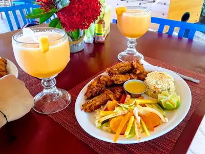 a table with a plate of food and two glasses of orange juice at Hotel Los Mangos El Salvador in El Cuco