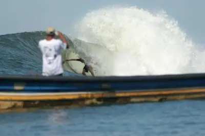 a man riding a wave on a surfboard in the ocean at Hotel Los Mangos El Salvador in El Cuco