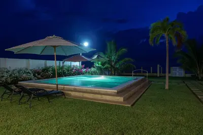 a swimming pool at night with an umbrella and chairs at Ayanna Beach Front in La Libertad