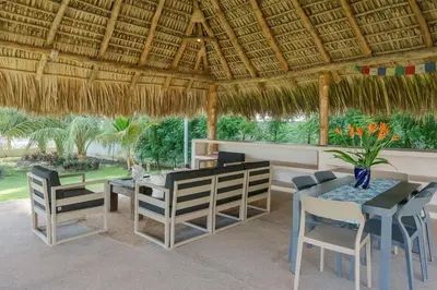 a patio with a table and chairs and a straw roof at Ayanna Beach Front in La Libertad