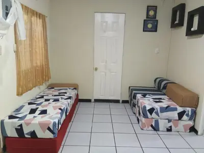 a room with two beds and a door in it at Casita Escondida- El Salvador in La Libertad