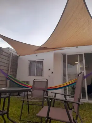 a patio with awning and chairs and a hammock at Casa flores Residencial Privada Nueva San miguel in San Miguel