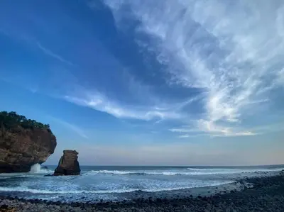 a beach with a large rock in the ocean at Jaco Mizata Beach and River in La Libertad