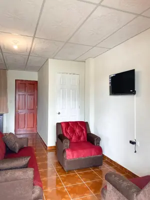 a living room with a red couch and a tv at MARIA III HOSTAL in Juayúa