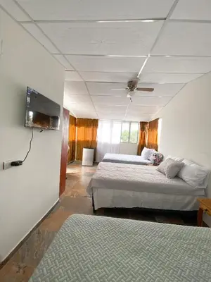 a bedroom with two beds and a flat screen tv at MARIA III HOSTAL in Juayúa
